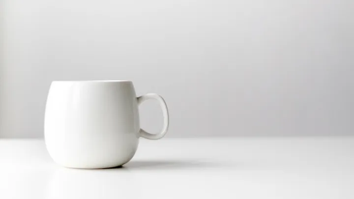 White ceramic coffee mug on a dark surface