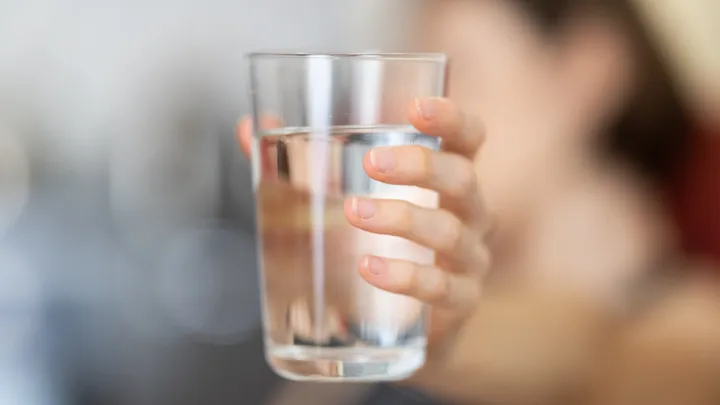 Person holding a clear glass of water