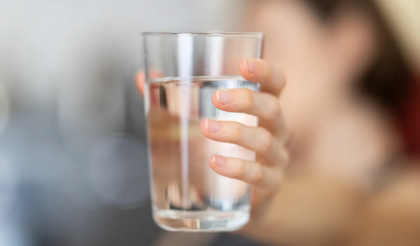 Person holding a clear glass of water