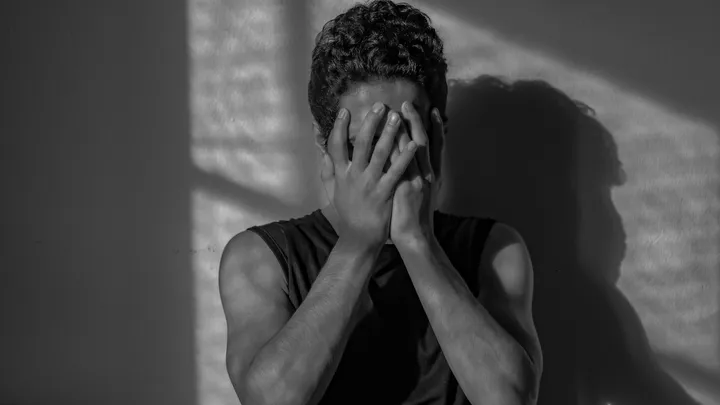 Man covering his face while experiencing head pain