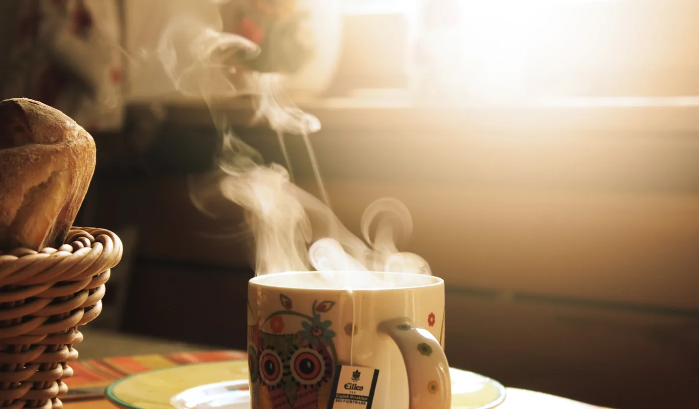 Green and white mug beside a meal on a wooden table