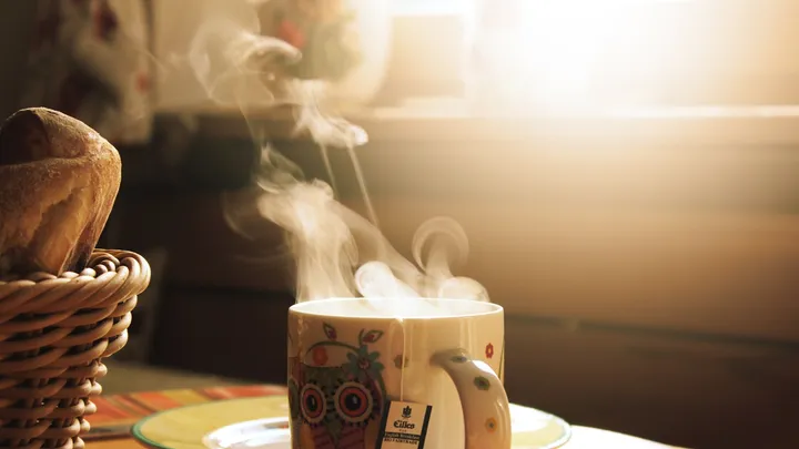 Green and white mug beside a meal on a wooden table