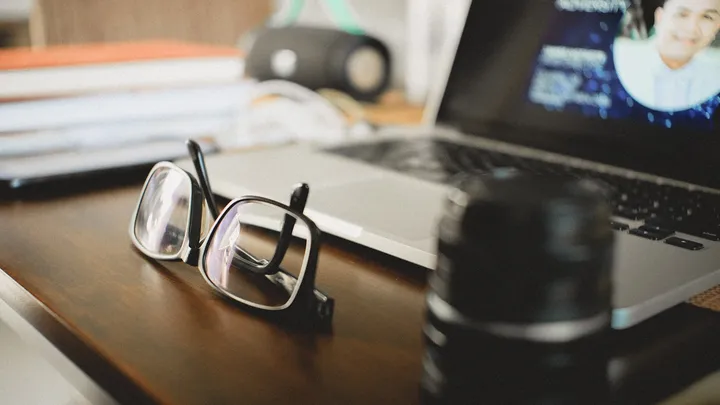 Eyeglasses resting beside a workspace after a headache behind the eyes