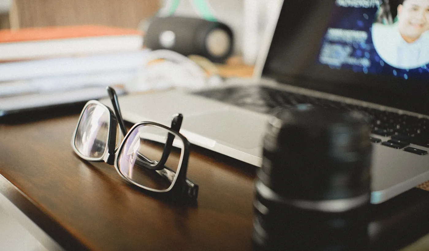 Eyeglasses resting beside a workspace after a headache behind the eyes