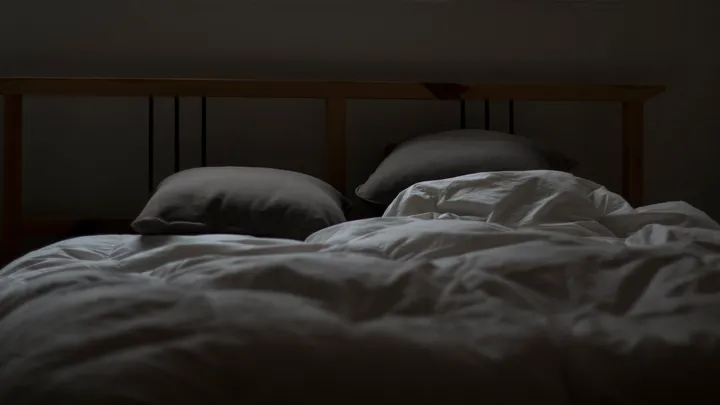 Empty bed representing a nighttime hypnic headache that wakes a person from sleep