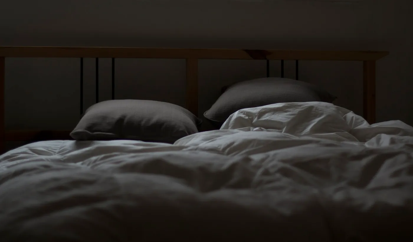 Empty bed representing a nighttime hypnic headache that wakes a person from sleep