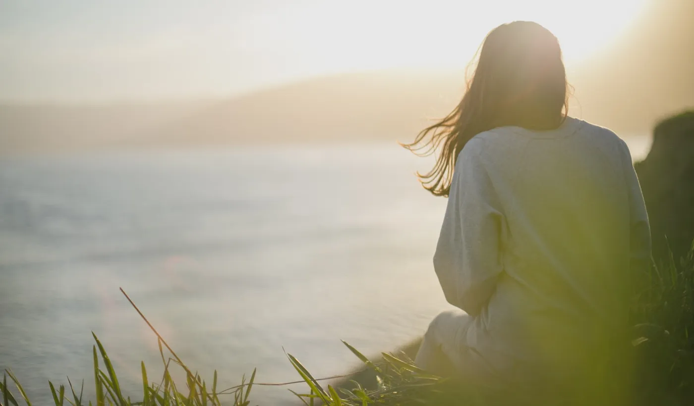 Woman facing the sea while waiting for migraine aura symptoms to pass