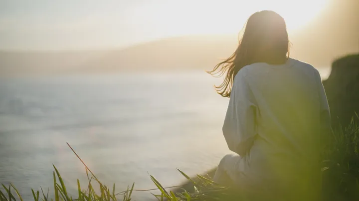 Woman facing the sea while waiting for migraine aura symptoms to pass