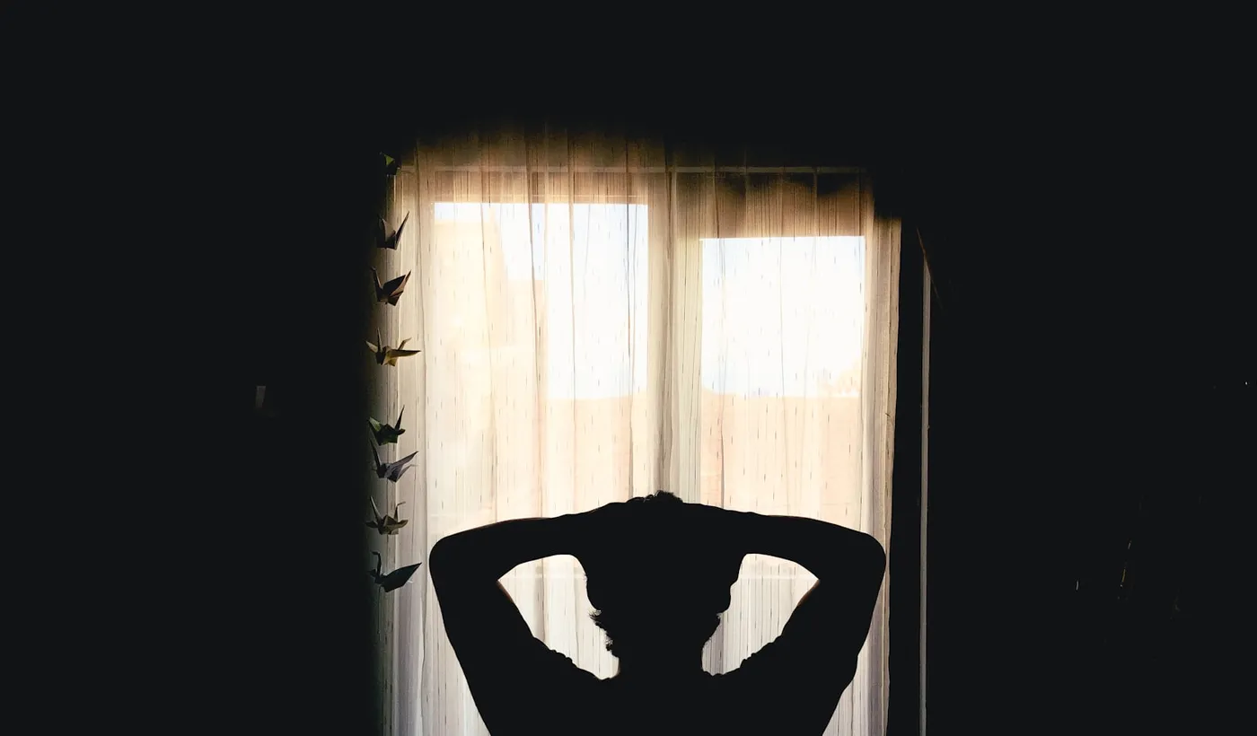 Silhouette of a tired person resting with both hands behind their head