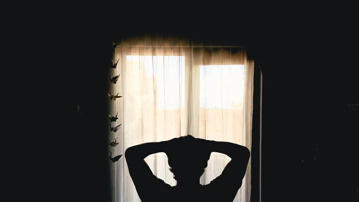 Silhouette of a tired person resting with both hands behind their head