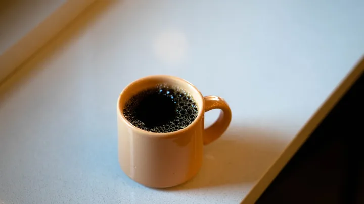 White ceramic coffee mug beside a window in the morning
