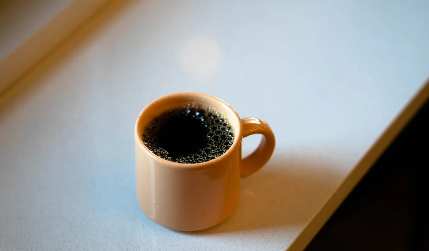 White ceramic coffee mug beside a window in the morning