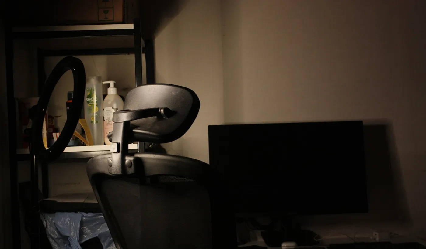 Dim home office with a computer screen, soft lamp, and low lighting